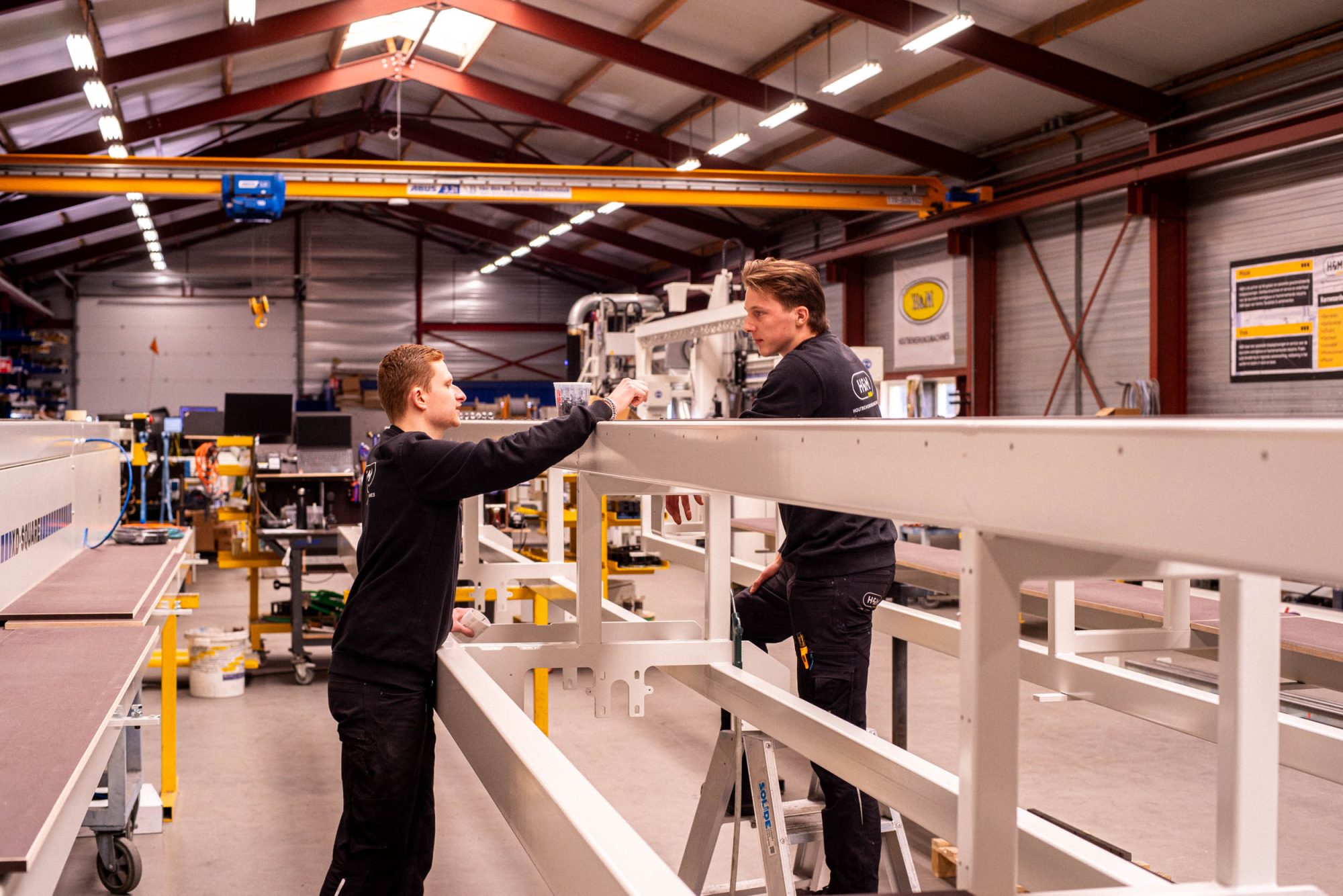 H&M houtbewerking collega's in gesprek aan het werk in de loods